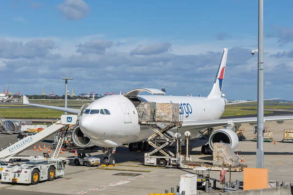 A wide-body freighter on the apron with cargo being loaded through its side door
