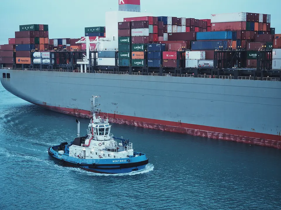 A harbour tug working alongside a large container ship