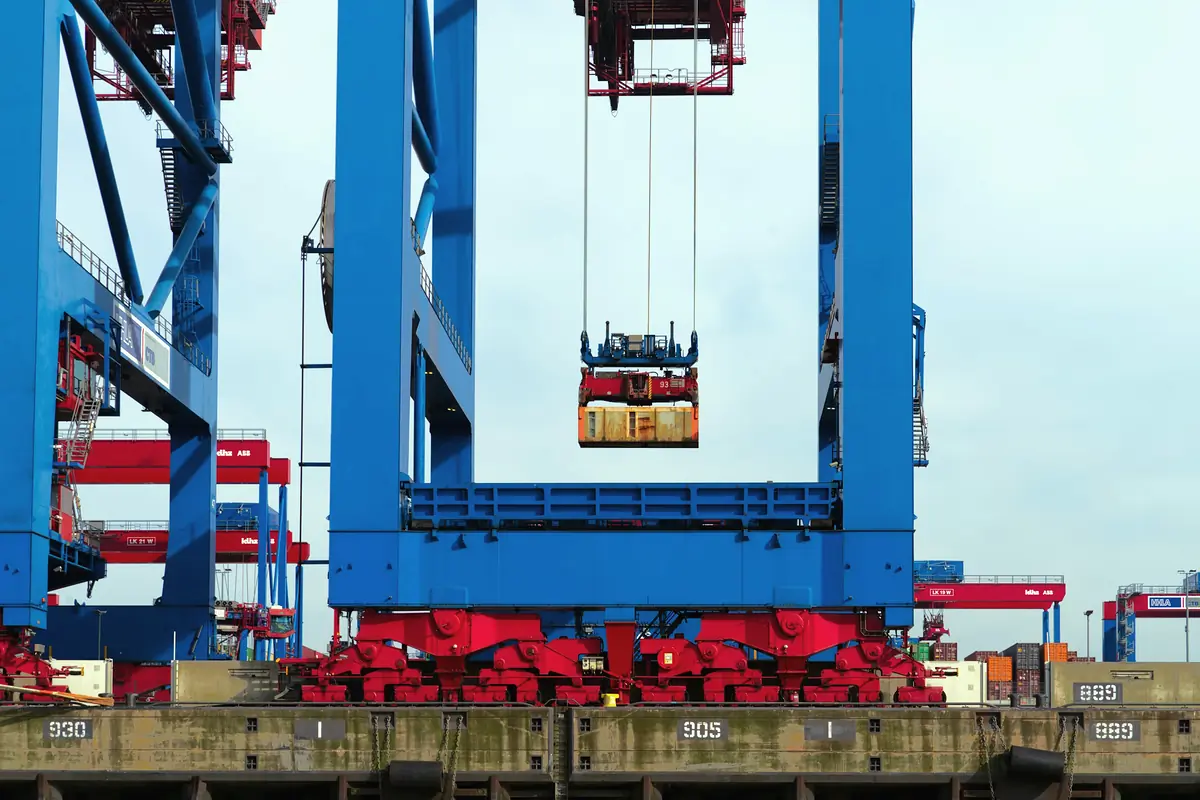 A gantry crane lifting a shipping container at a terminal