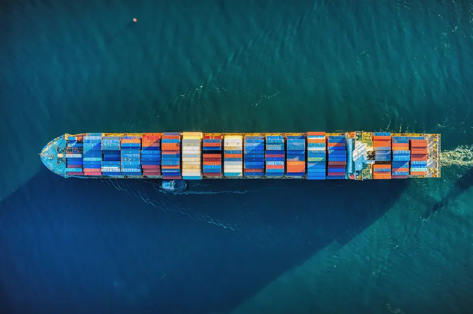 Top-down view of a container ship loaded with coloured containers on deep blue water